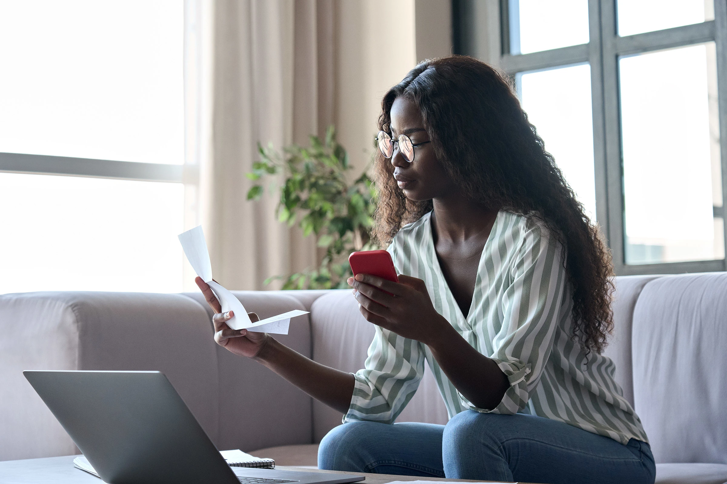 Young woman pays bills online using phone