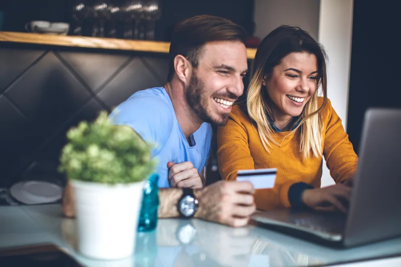 Couple laughing while paying a bill online together