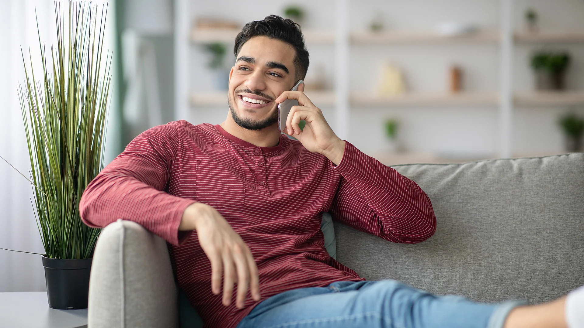 Happy middle eastern man at home talking on the phone