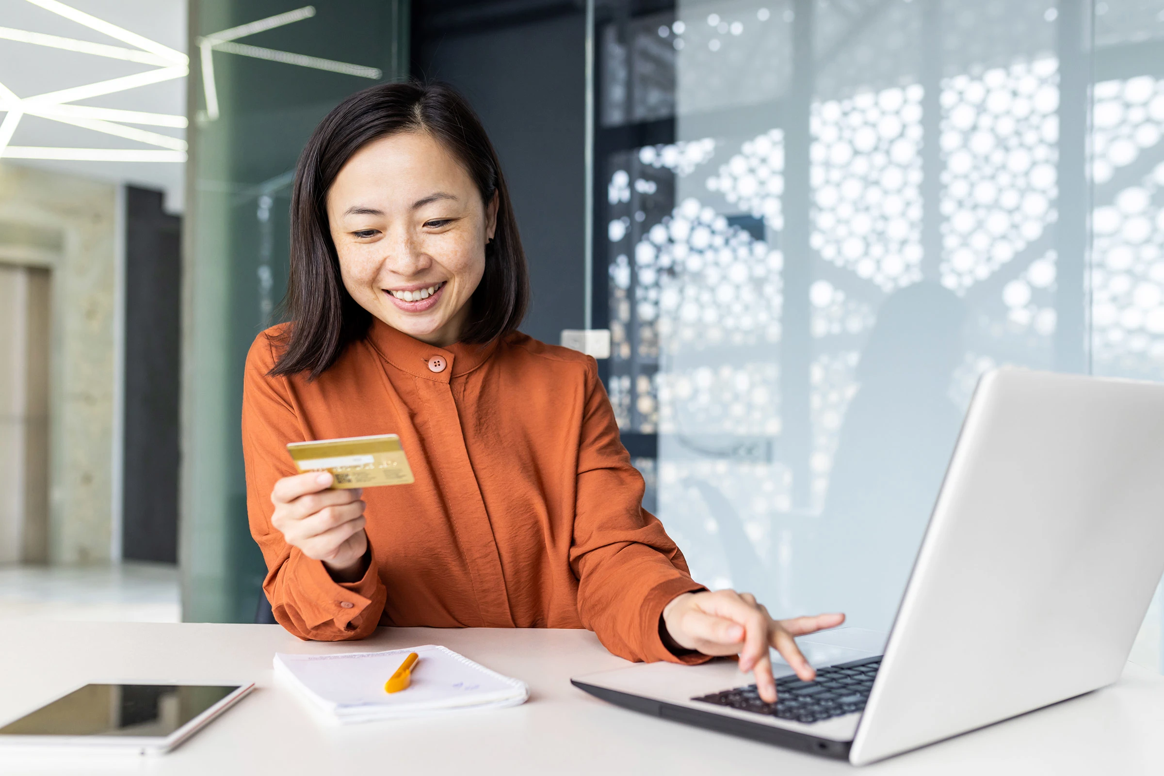 Happy Asian woman using credit card at laptop