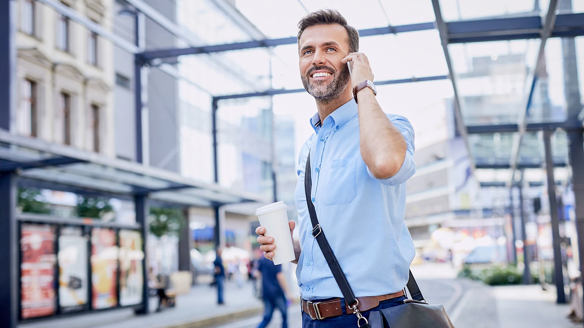 Business man using phone while waiting for public transportation