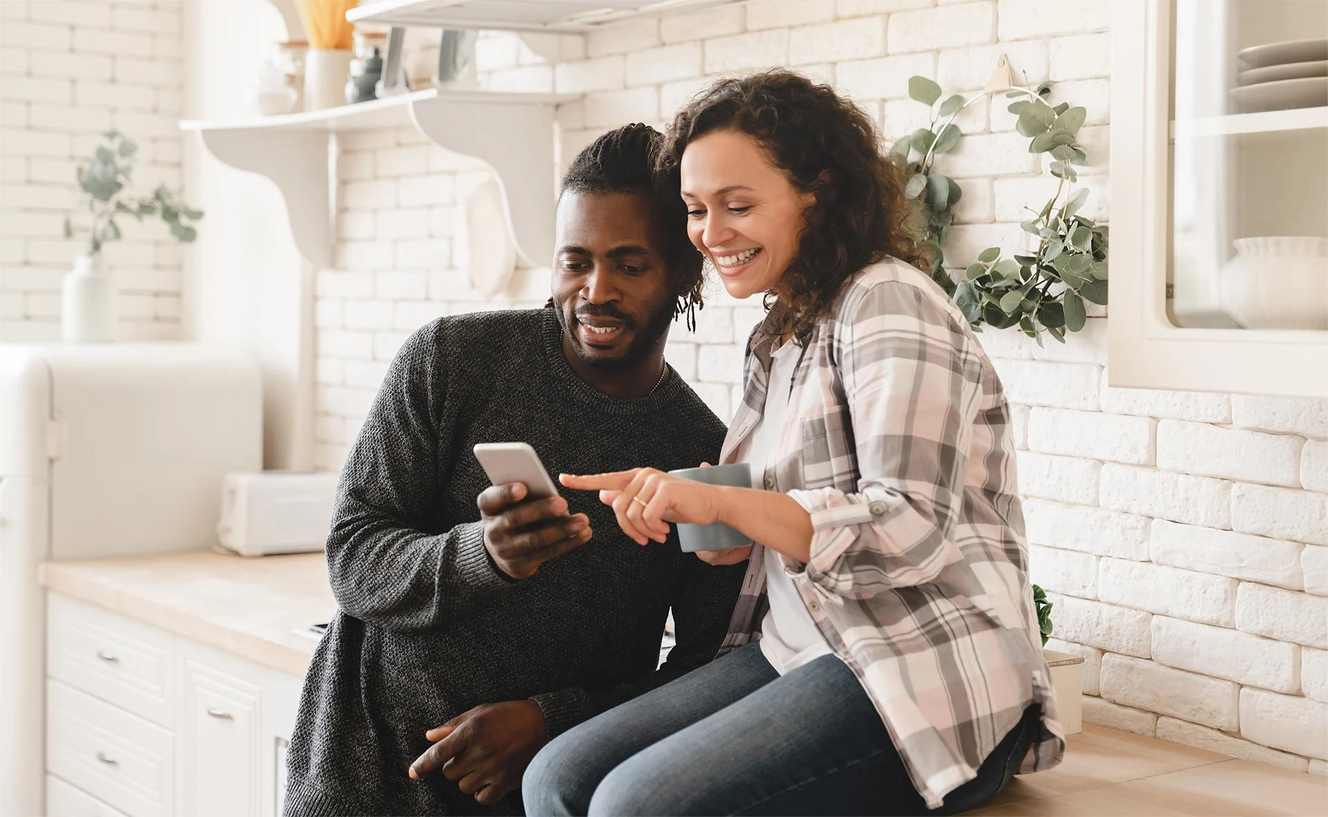 Couple using phone in kitchen to surf the web