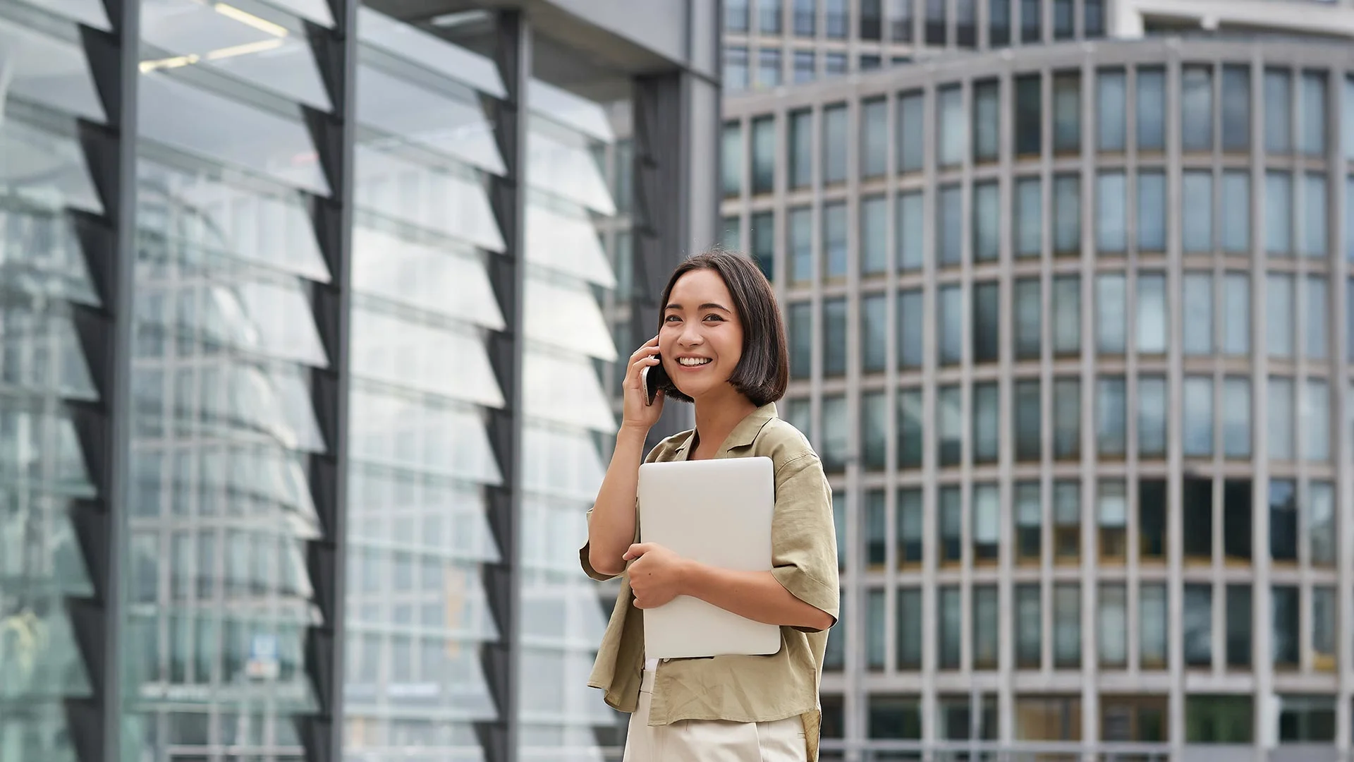Stylish Asian woman on phone while walking through city