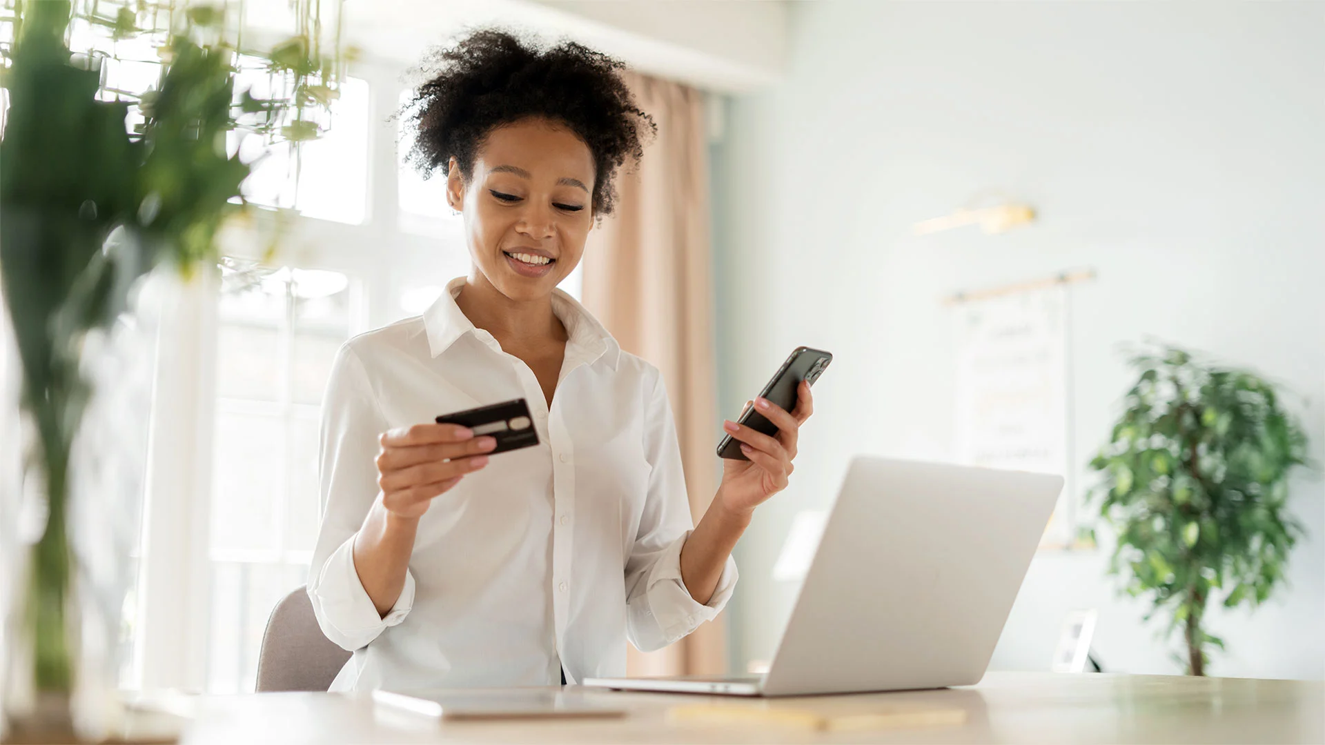 Woman using phone and laptop to make online purchase