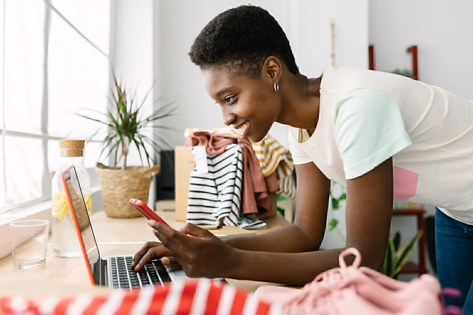 small business african woman owner with mobile phone on laptop
