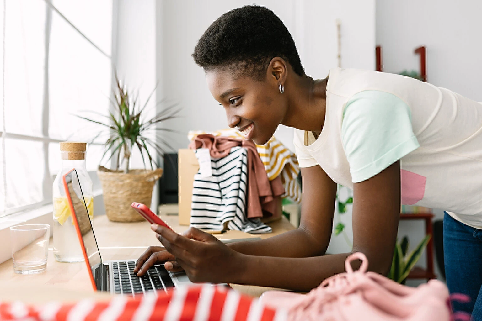 small business african woman owner with mobile phone on laptop