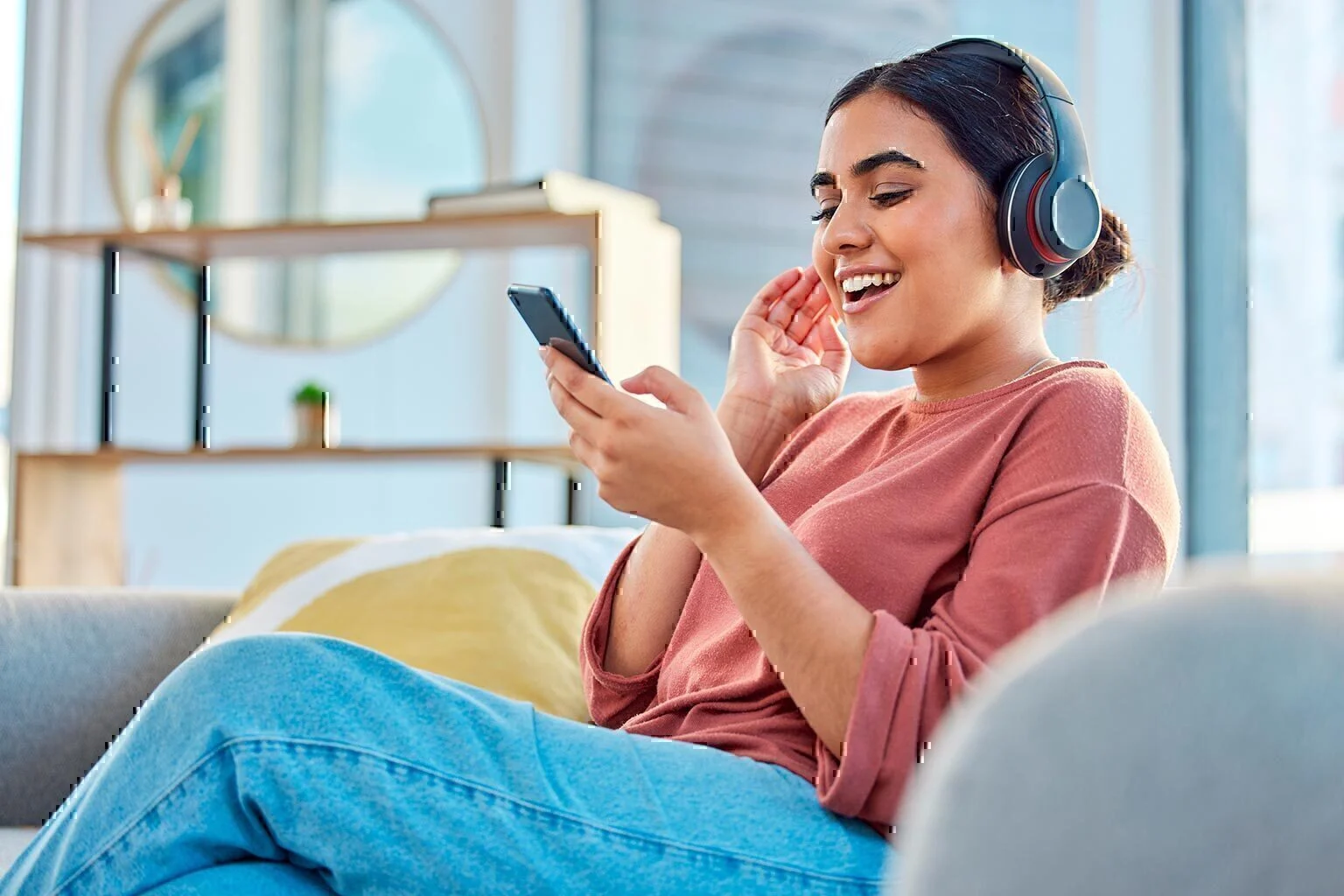 happy woman headphones and smartphone in living room