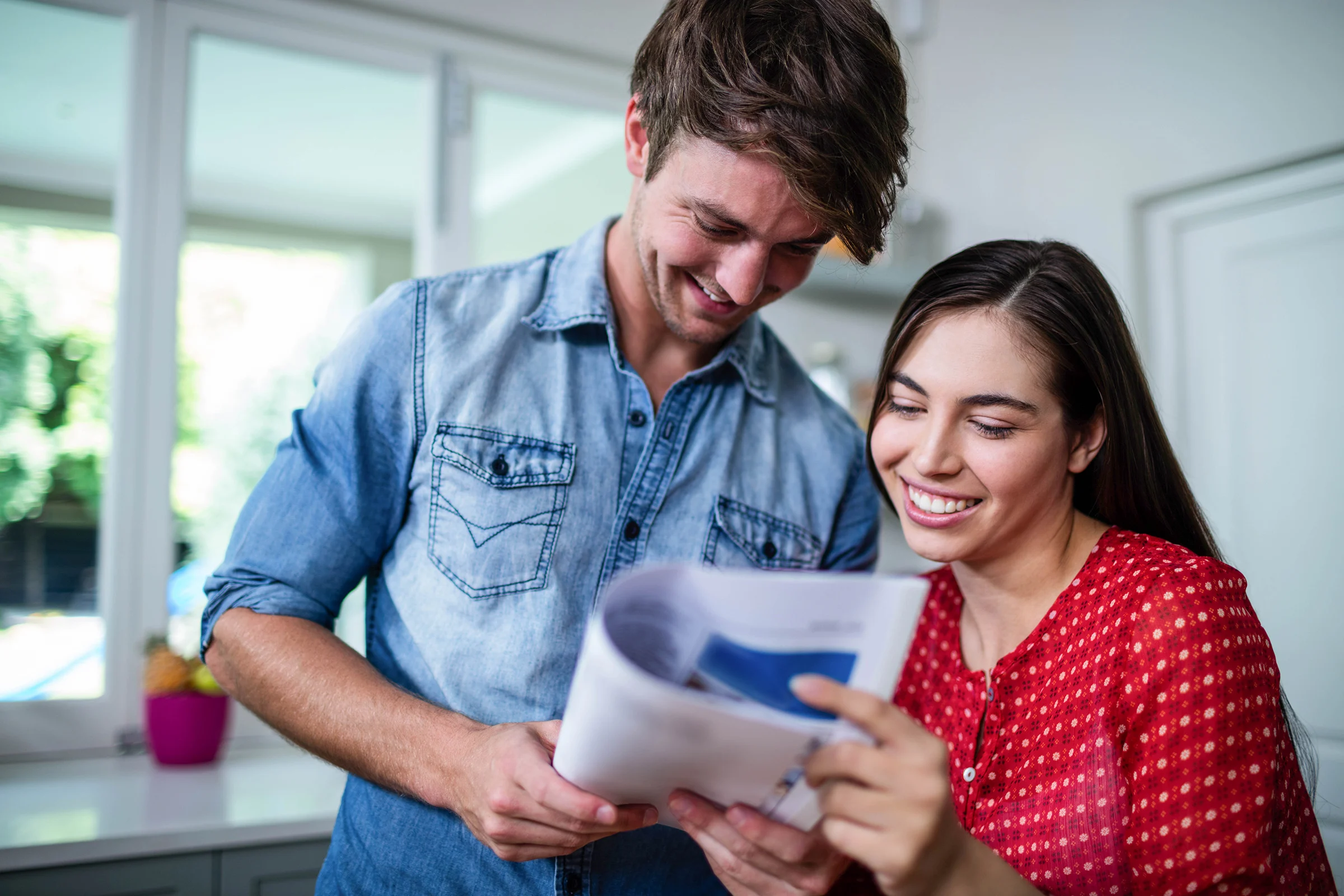 Happy couple reading newspaper at home
