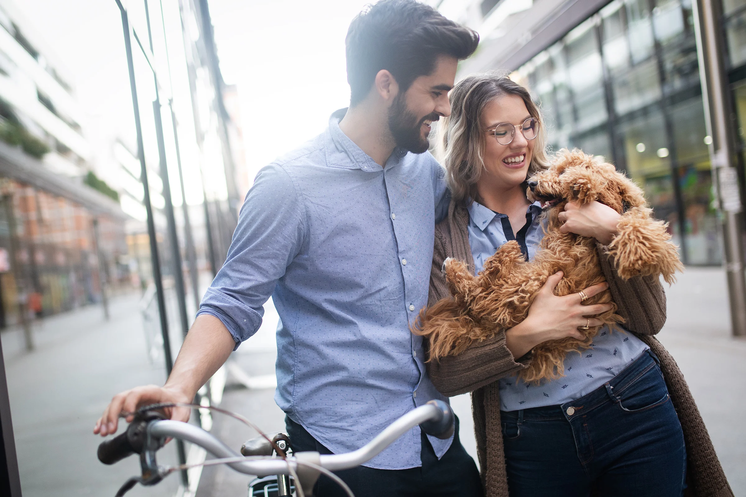 Beautiful couple walking dogs and bicycles outdoors in city