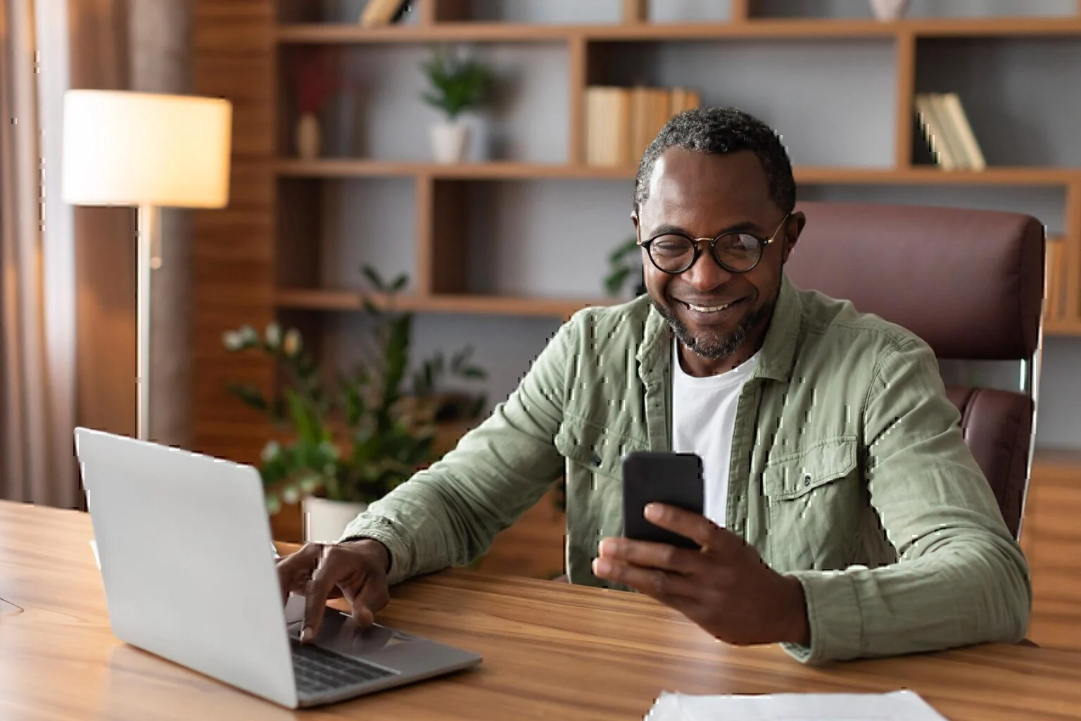 Business man in home office using phone and computer