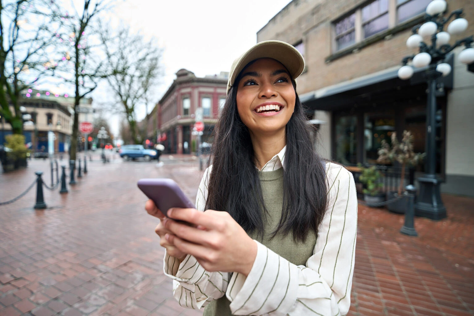 Happy Asian teen girl using smartphone standing on city street with smartphone.