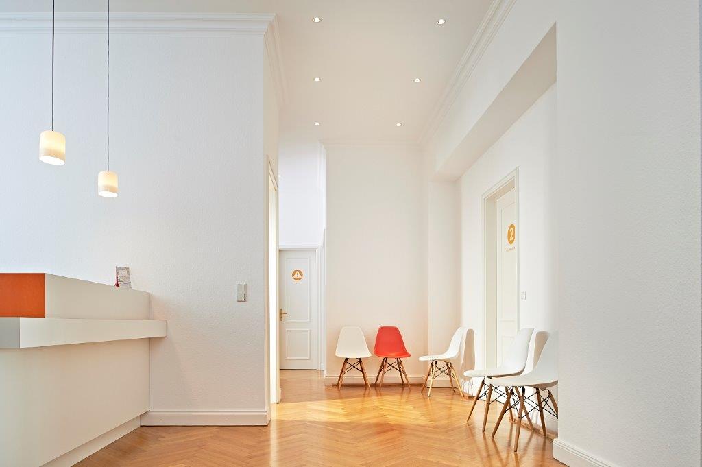 Empfangsbereich mit Tresen und Stühlen im Wartebereich.