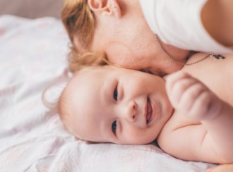 Baby smiling as mum kisses their cheek_1080x800