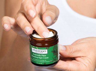 Antipodes Avocado Pear Nourishing Night Cream_one hand holds small glass jar of moisturising cream as the other hand is dipping index finger into the cream - 1080 x 800