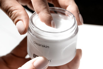 PCA Clear Skin - hands holding the product jar while index finger dips into the cream - 670 x 452