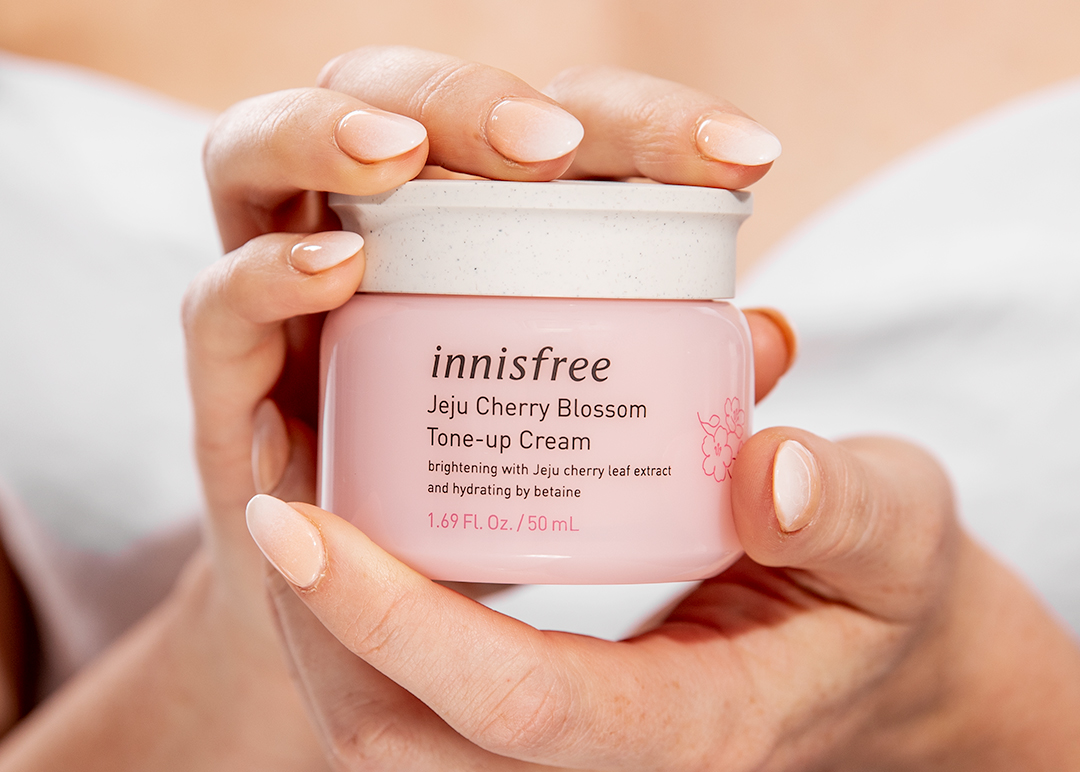 Korean Skincare - Innisfree Cherry-Blossom-Tone-Up-Cream  - two hands with manicurd nails holding the product jar - 1080 x 772