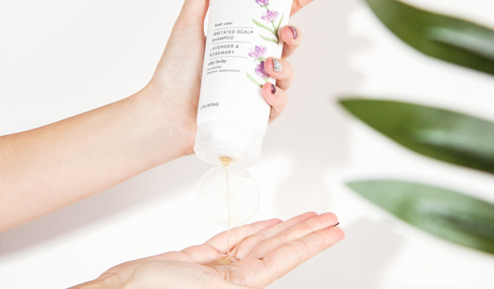 Green People Irritated Scalp Shampoo for Normal/Oily Hair - one hand holds bottle while pouring product into palm of other hand - 700 x 410