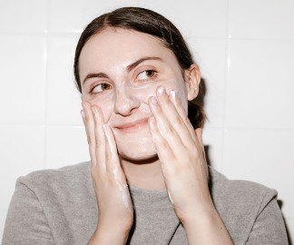 How Long Do You Leave Cleanser On Your Face? [model cleaning face in white bathroom]