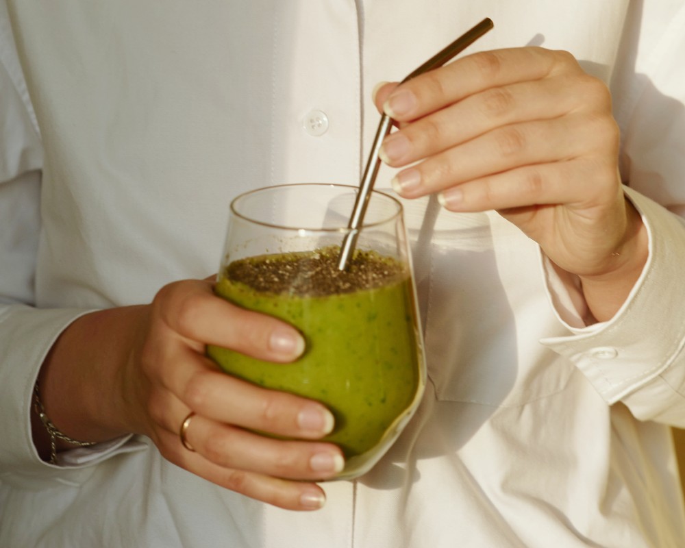 organic certification australia hands holding a glass of green smoothie with eco-friendly reusable metallic straw