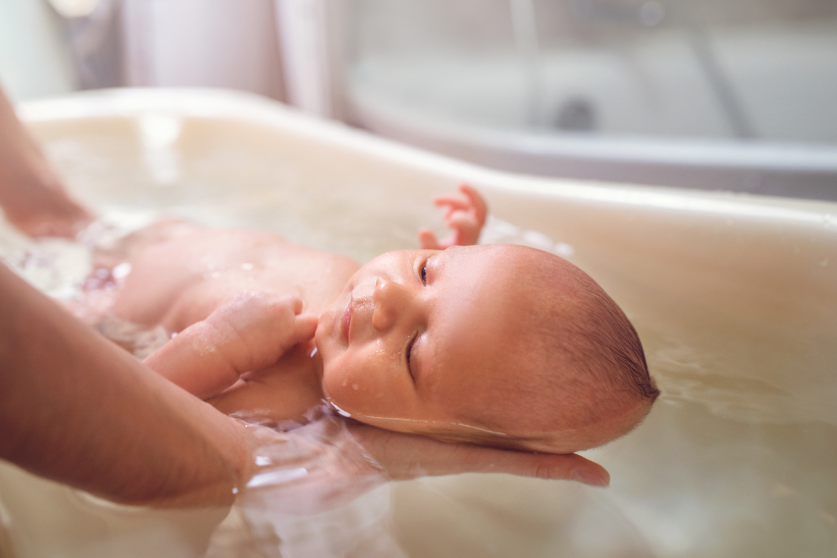 best organic baby bath wash - two hands are holding up baby in a small baby bath tub - 1200 x 800