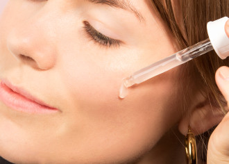  TheOrdinary Buffet - woman applying serum to her cheek from a glass dropper - 1080 x 772