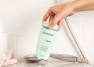 Kérastase Specifique Balancing Shampoo - shampoo is being poured out of bottle into palm of hand. The background is shower tiles - 670 x 439