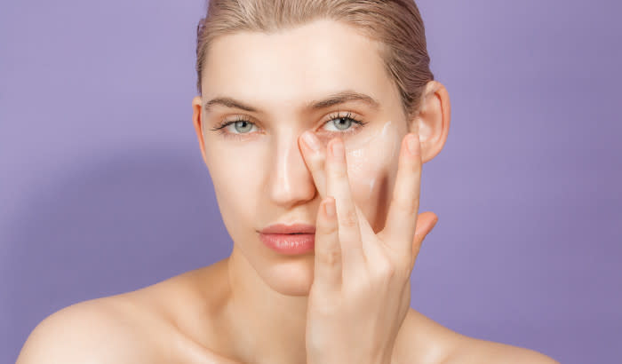 La Roche-Posay SPF 50+ - Woman in front of light purple background applying sunscreen to face with fingers - 700 x 410
