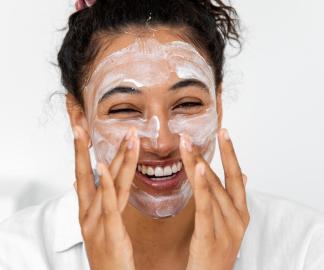 Top Natural and Organic Face Cleansers_model laughing and applying cream cleanser to her face