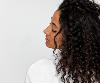 5 Tips for Taming Curly, Frizzy Hair Without Making it Greasy_the side of a woman with long dark curly hair_1080x900