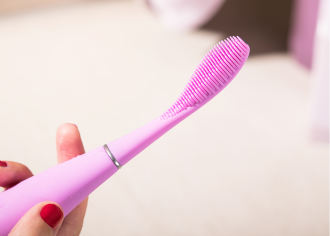 Foreo ISSA Play Sonic Toothbrush in Pearl Pink - A hand with red nails holds electric toothbrush - 1080 x 771