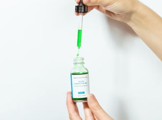 best-serums-for-acne-scars_SkinCeuticals Phyto Corrective Gel_hands lifting dropper from bottle of green serum - 1080 x 771