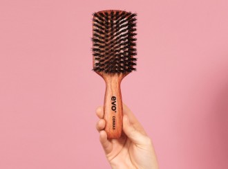 Best Hair Brush for Frizzy Hair_evo Conrad Boar Bristle Paddle Brush_hand holding wooden brush in front of pink background-1080x800