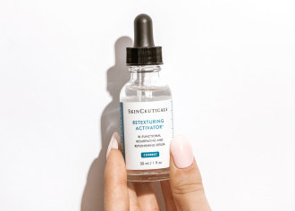Skinceuticals Retexturizing Activator - hand holding small glass bottle with black dropper lid - 1080 x 771
