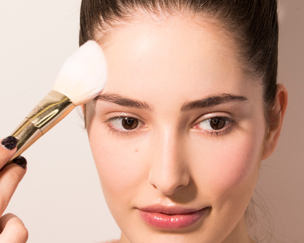 best-full-coverage-powder-foundation_woman using makeup brush to apply powder