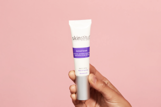 Adore Beauty - hand holding tube of Skinstitut Retinol in front of pink background - 1200 x 800