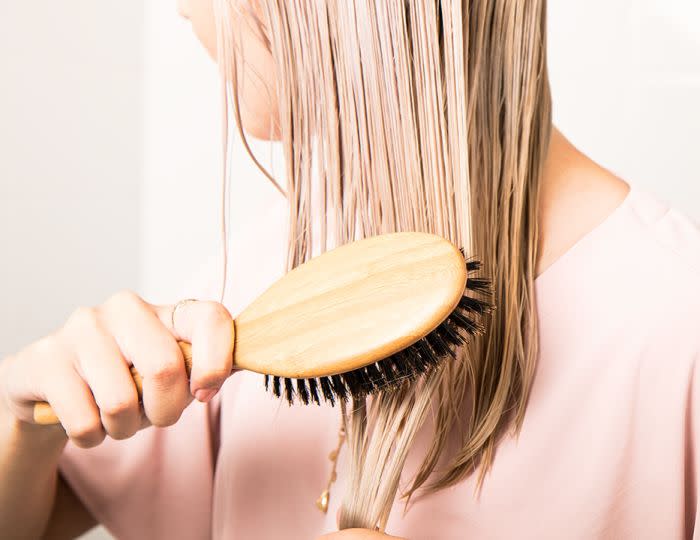 Woman with blonde hair using a wooden brush