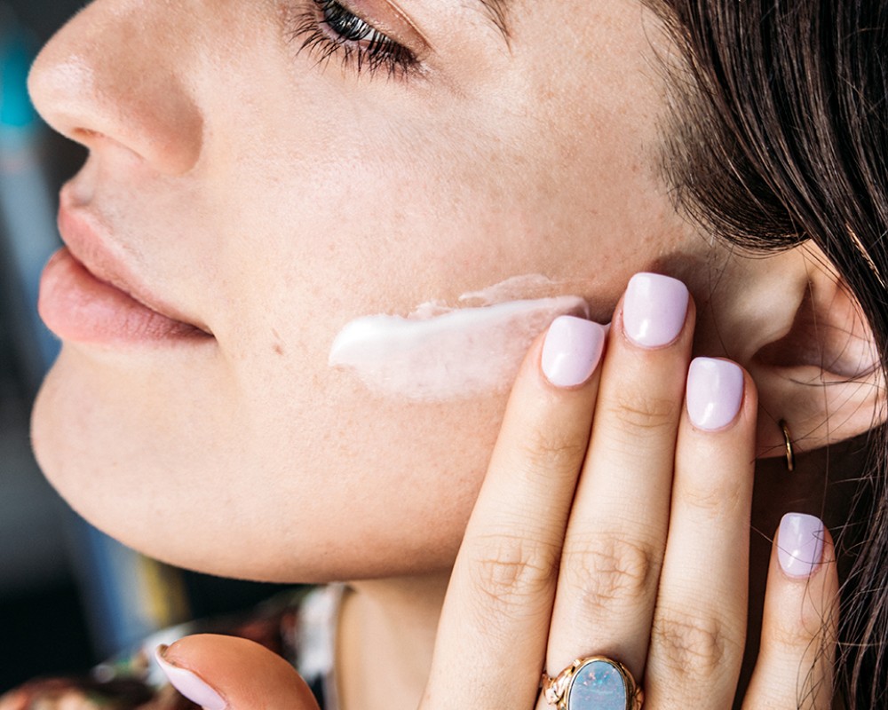 6 French Beauty Products That Make Us Feel Like We’re In Paris_woman applying face cream to her cheek