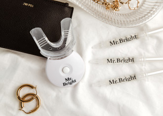 Mr Bright Whitening Kit With LED - flat lay on white sheets, next to gold earrings, a black purse and a dish of gold jewellery - 1080 x 771