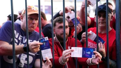 Liverpool fans stuck outside the ground show their match tickets