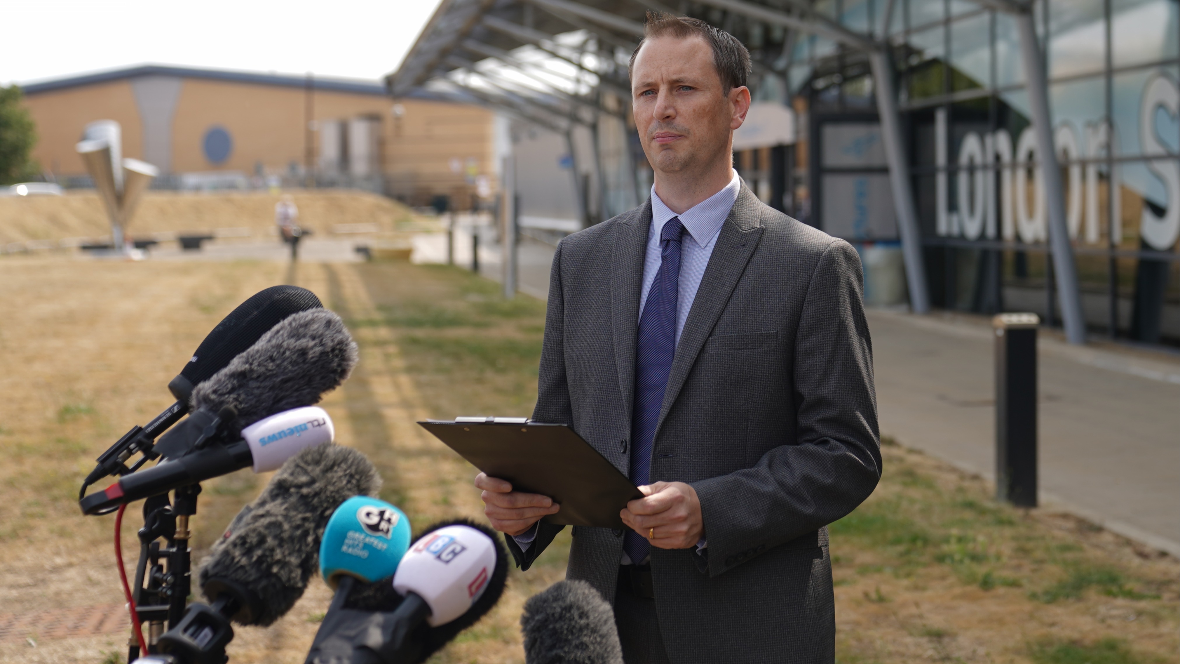 Morgan Cronin speaking to reporters in front of assembled microphones