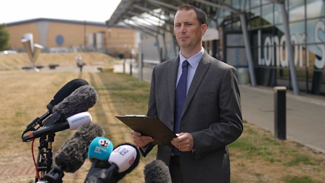 Morgan Cronin speaking to reporters in front of assembled microphones