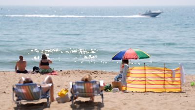People enjoying the sunny weather on Bournemouth Beach in Dorset.