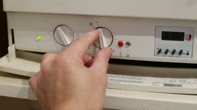 A person adjusts their gas boiler 