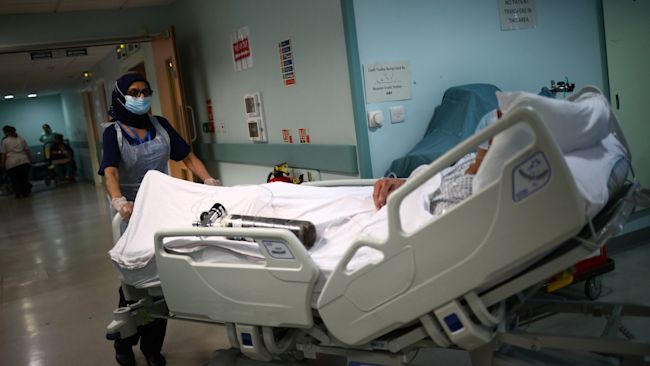 Medical staff transfer a patient through a corridor at The Royal Blackburn Teaching Hospital in East Lancashire during the outbreak of the coronavirus disease.