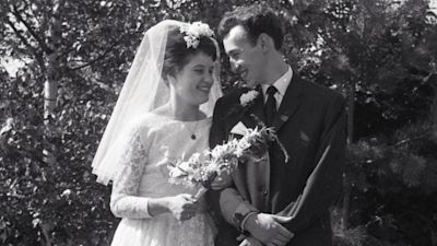 A bride and groom standing arm and arm in a garden