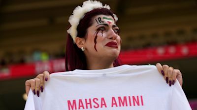 An Iranian protestor holding a football shirt with the name 'Masha Amini' emblazoned on the back.