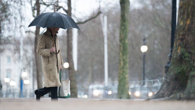 A woman walks through central London in the rain.