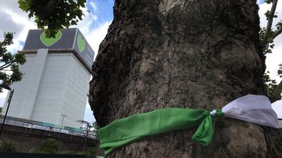 A ribbon is tied around a tree near Grenfell Tower in London, Sunday, June 14, 2020. Britain is marking the third anniversary of the Grenfell Tower fire with a virtual church service to remember the 72 people who died in the blaze. Sunday marks three years since a small kitchen fire in the west London public-housing block turned into the worst domestic blaze in the country since World War II.(AP