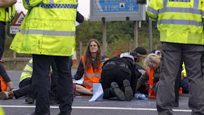 Police officers work to free protesters who had glued themselves to a slip road at Junction 4 of the A1(M), near Hatfield, where climate activists carried out a further action after demonstrations which took place last week across junctions in Kent, Essex, Hertfordshire and Surrey. Picture date: Monday September 20, 2021. Steve Parsons/PA