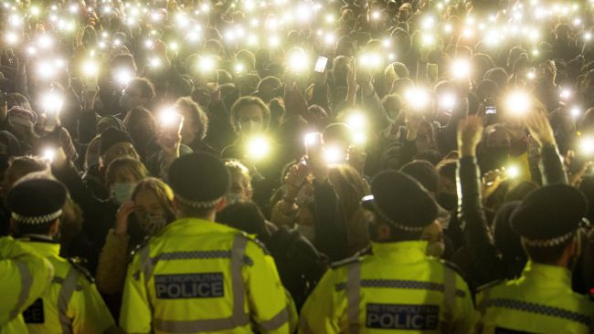 people in the crowd turn on their phone torches as they gather in Clapham Common, London, for a vigil for Sarah Everard